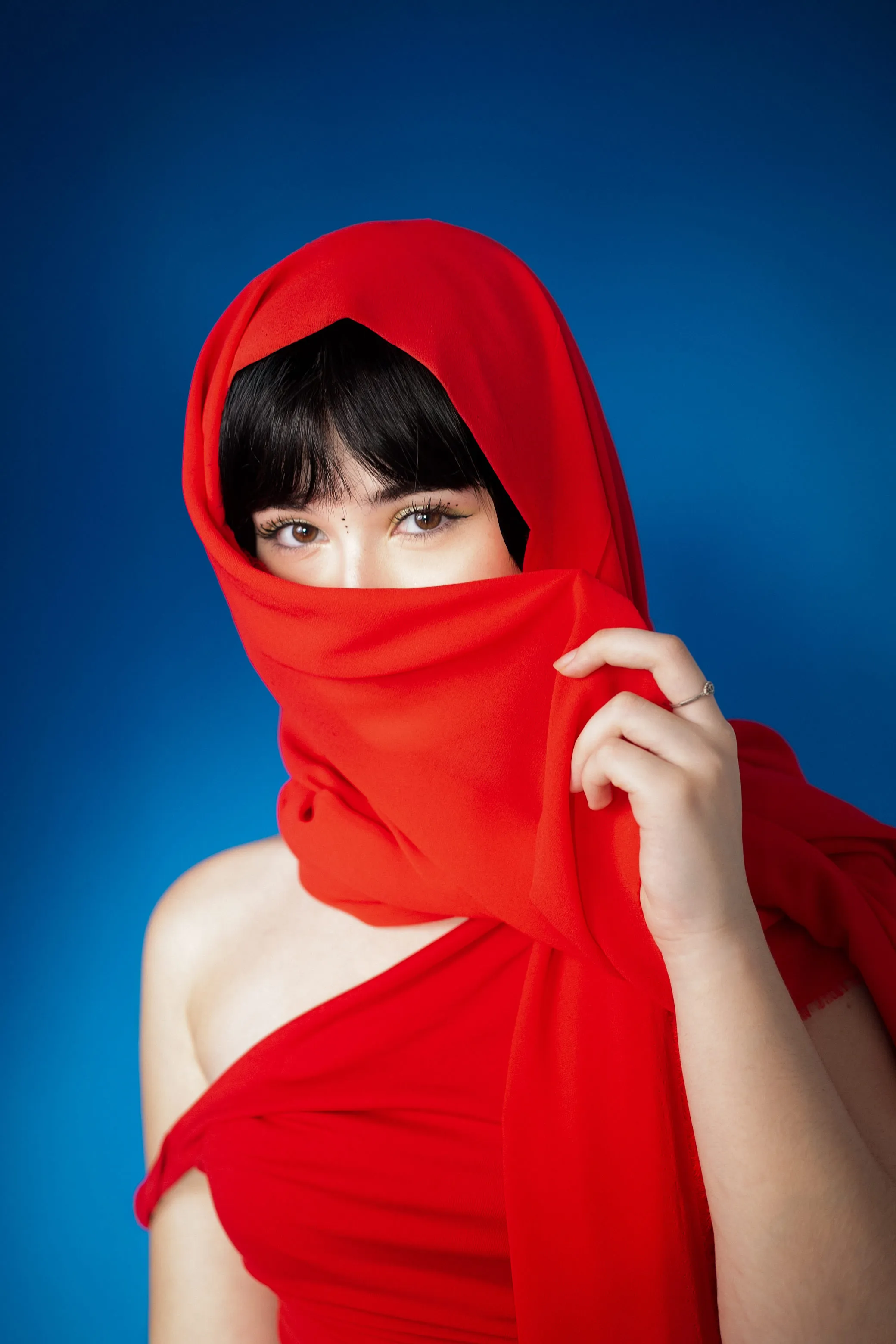 Retrato editorial com véu vermelho sobre fundo azul